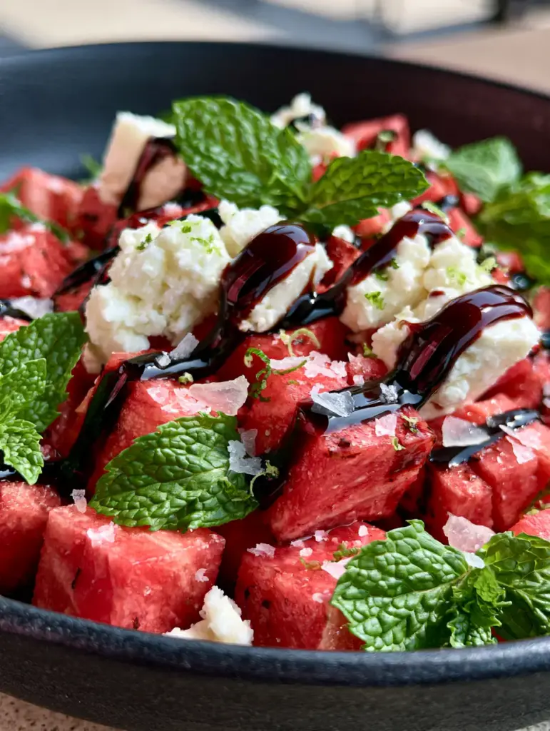 Extreme macro photography of ruby-red watermelon cubes and glossy balsamic ribbons. (watermelon salad)