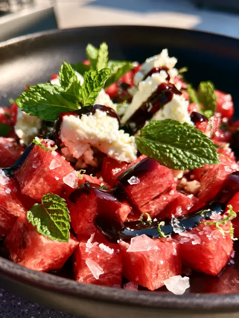 Watermelon Salad with Feta, Mint, and Thick Balsamic Glaze 1 Overhead view of watermelon salad with emerald mint chiffonade and white feta crumbles. (watermelon salad)