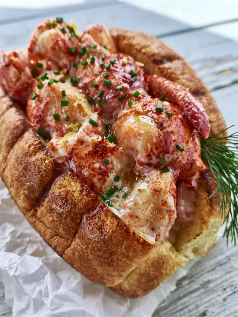 Ultra close-up of succulent chilled lobster claw meat glistening with butter glaze inside a golden-brown toasted brioche bun. (Lobster Rolls)
