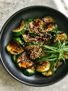 High-angle shot of emerald green zucchini half-moons with golden-brown sear marks in a garlic soy glaze. (Zucchini stir fry recipe)