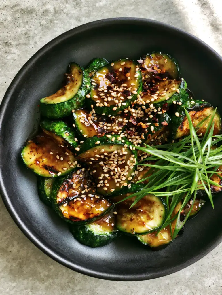 High-angle shot of emerald green zucchini half-moons with golden-brown sear marks in a garlic soy glaze. (Zucchini stir fry recipe)