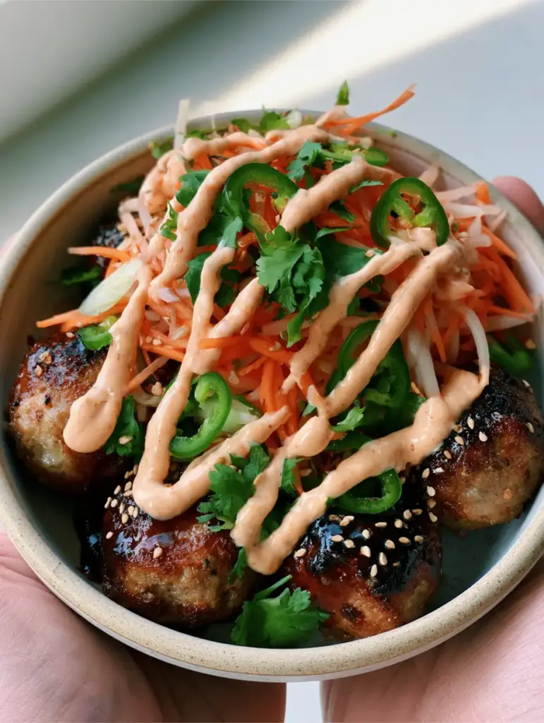 Banh Mi Meatballs with Sticky Hoisin-Honey Glaze and Pickled Veggies 1 Close-up texture of seared pork meatballs with a thick dark umami glaze and sesame seeds.