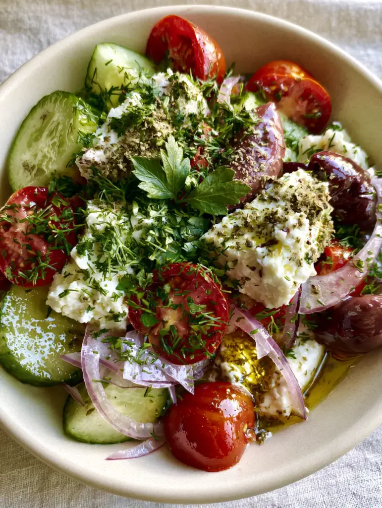Macro photo showing the shimmering golden vinaigrette on thick-cut Persian cucumbers in a Mediterranean feta salad.