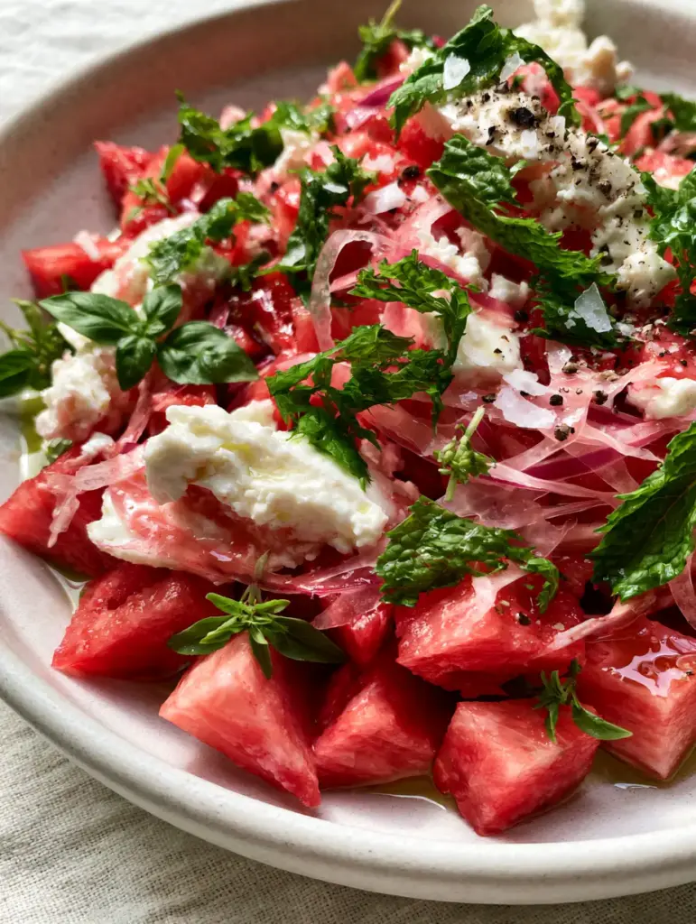 Watermelon Recipes: The Ultimate Chilled Watermelon Feta Salad with Fresh Herbs 1 Close up of paper-thin red onions and torn mint on a red watermelon salad.