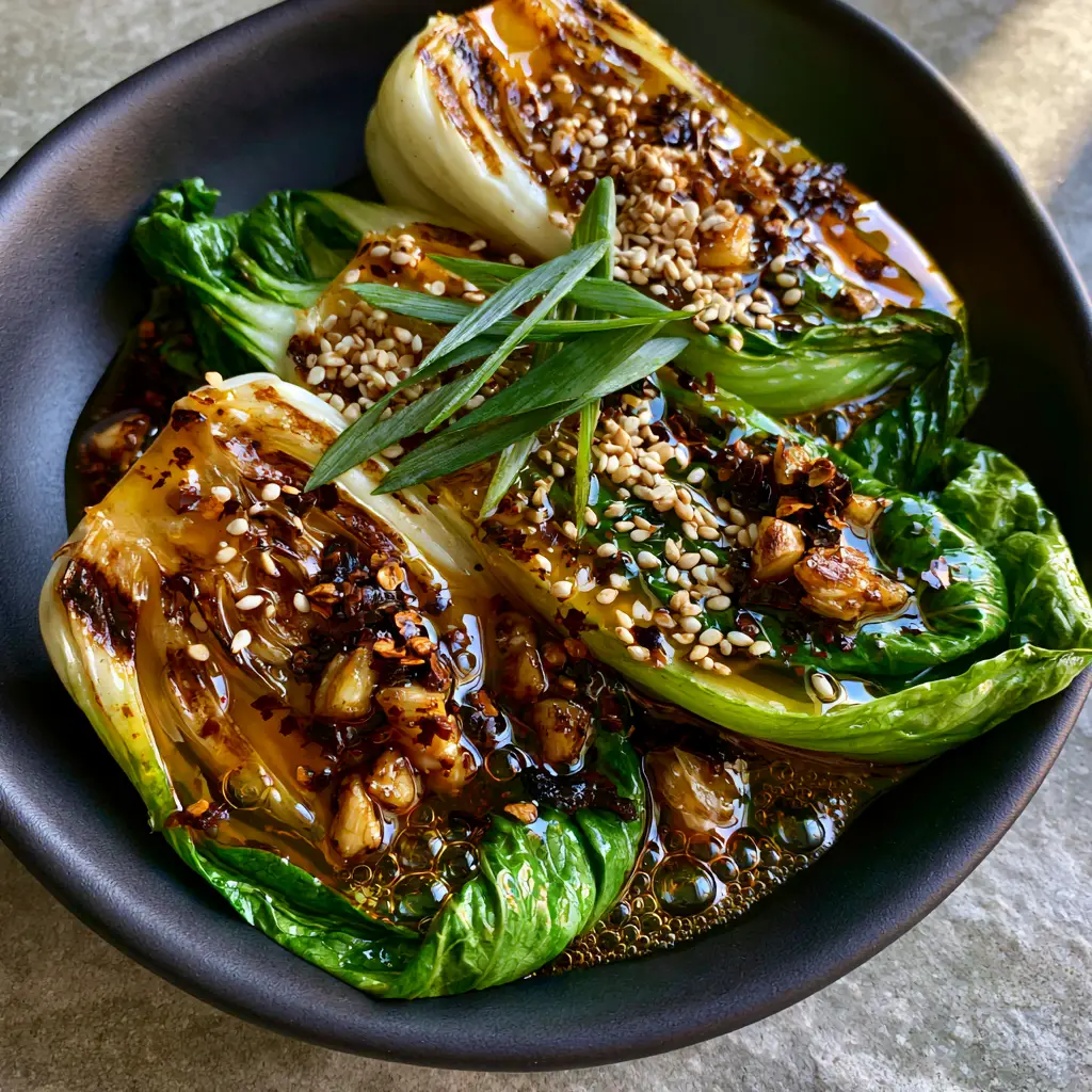 Spicy Garlic Bok Choy with Sizzling Chili Oil and Toasted Garlic 2 Macro photo of seared baby bok choy showing vibrant emerald leaves and toasted garlic bits in amber oil. (Spicy Garlic Bok Choy)