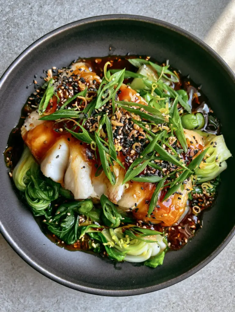Top-down view of ginger soy cod garnished with black and white sesame seeds and diagonal scallions.