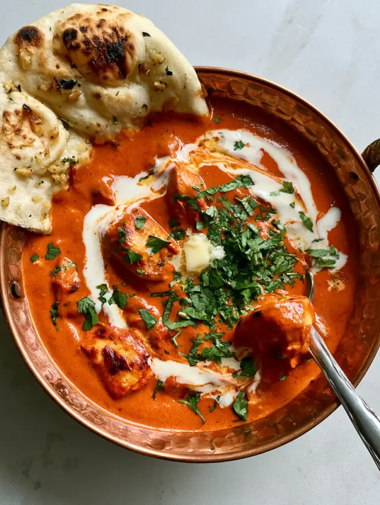 Easy Indian recipes: The Ultimate Creamy Butter Chicken and Blistered Garlic Naan 1 Pan-seared chicken thighs simmering in a vibrant tomato sauce next to charred garlic naan.
