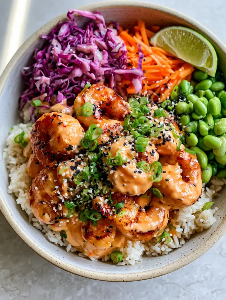 Close up of pan-seared shrimp with golden-charred edges coated in thick sriracha mayo glaze in a rice bowl.