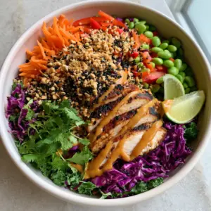 Close up of seared chicken breast strips with grill marks on top of a Thai chicken salad with peanut dressing.